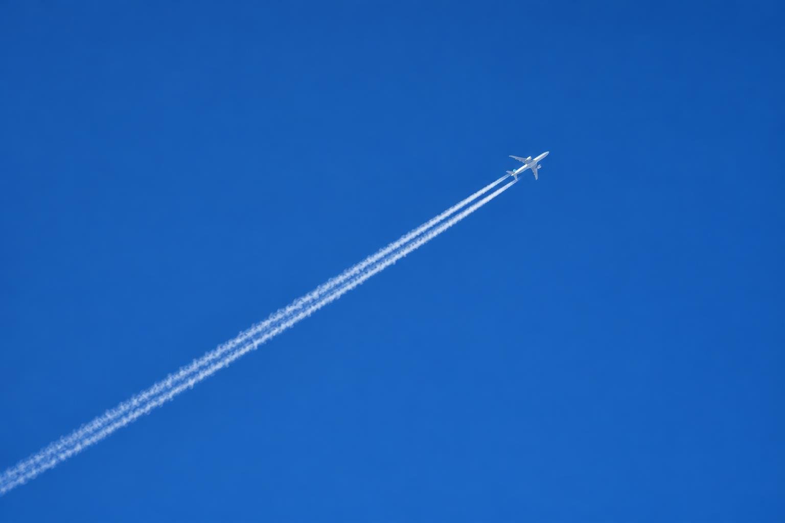 A plane leaving a contrail across a clear blue sky